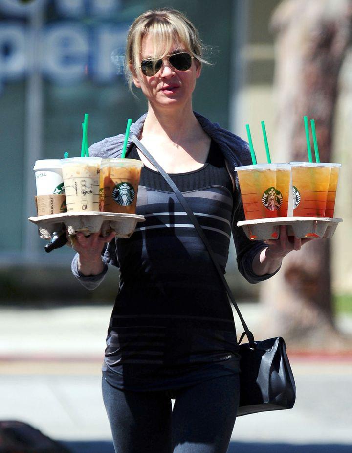 professional carrying two trays of to-go cups
