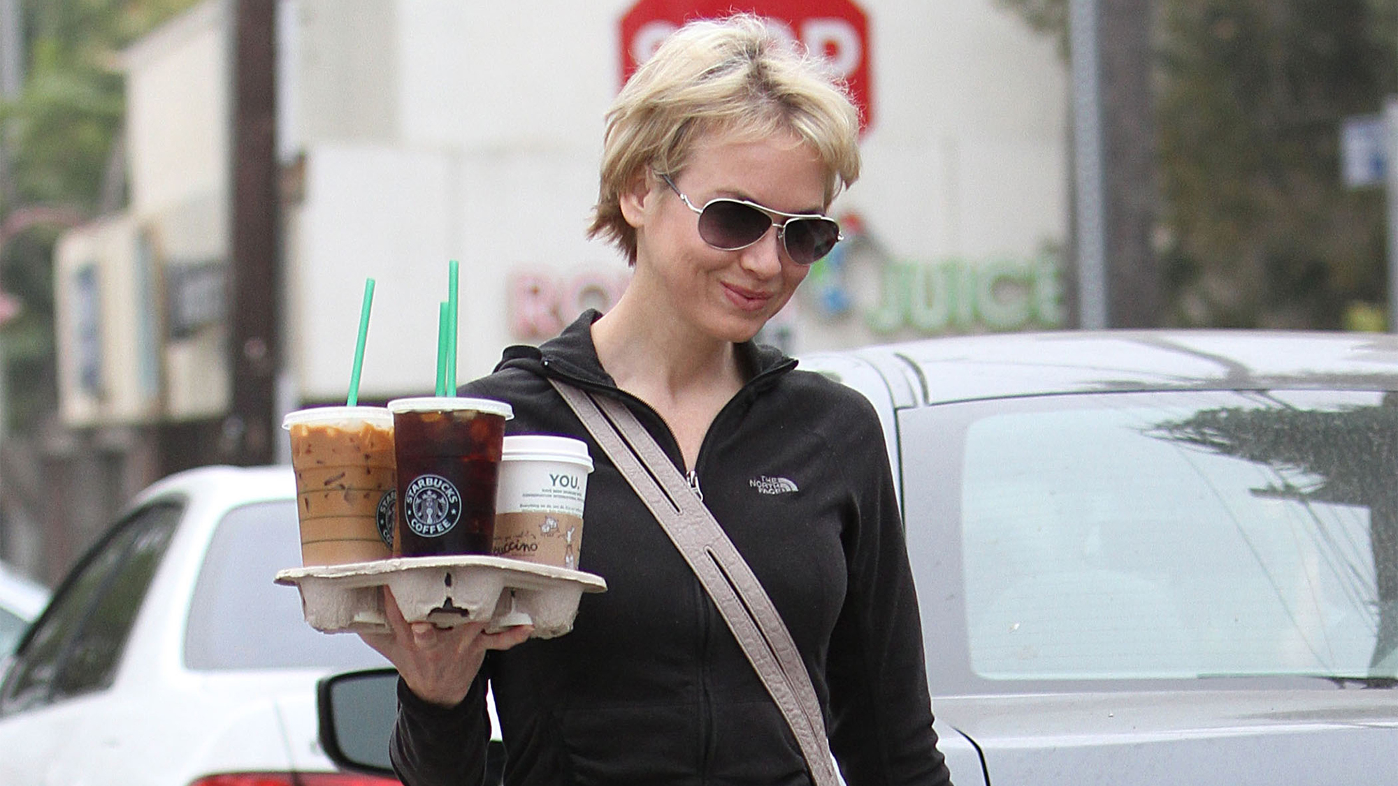 hands carrying iced to-go cups past a juice bar